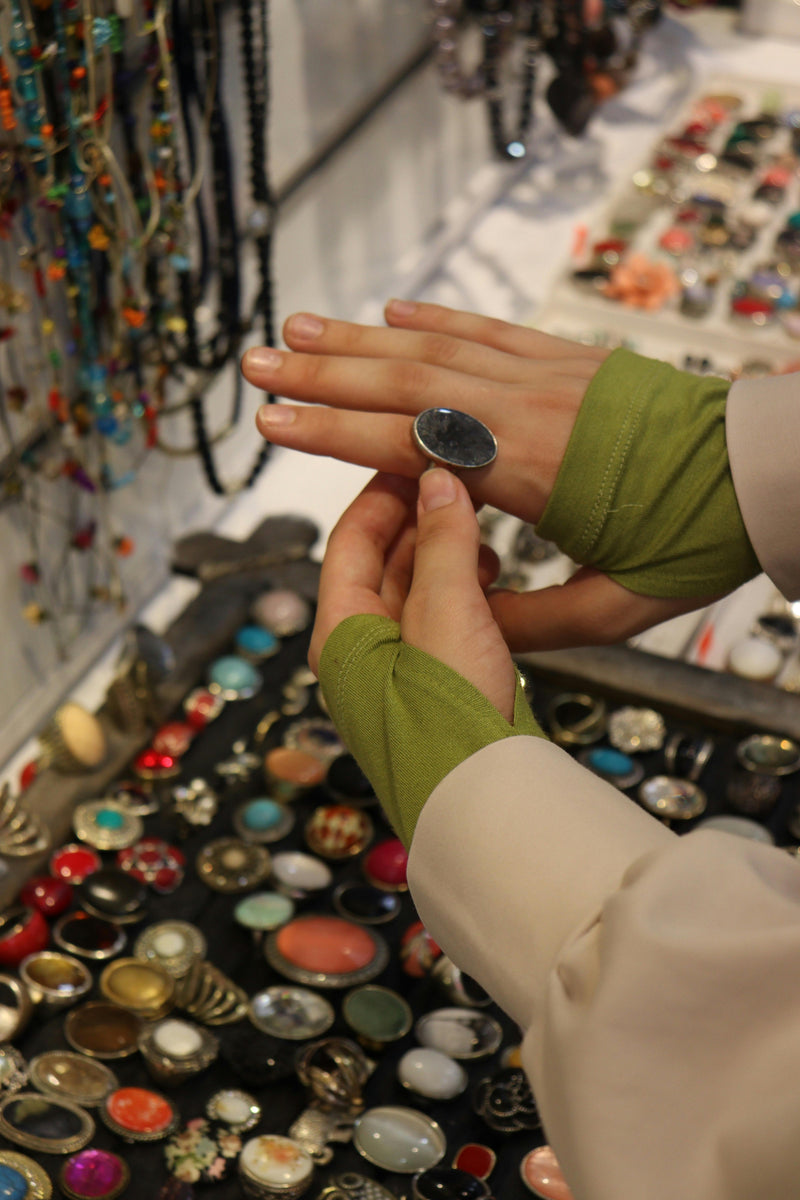 Person holding a ring in front of a display of colorful jewelry